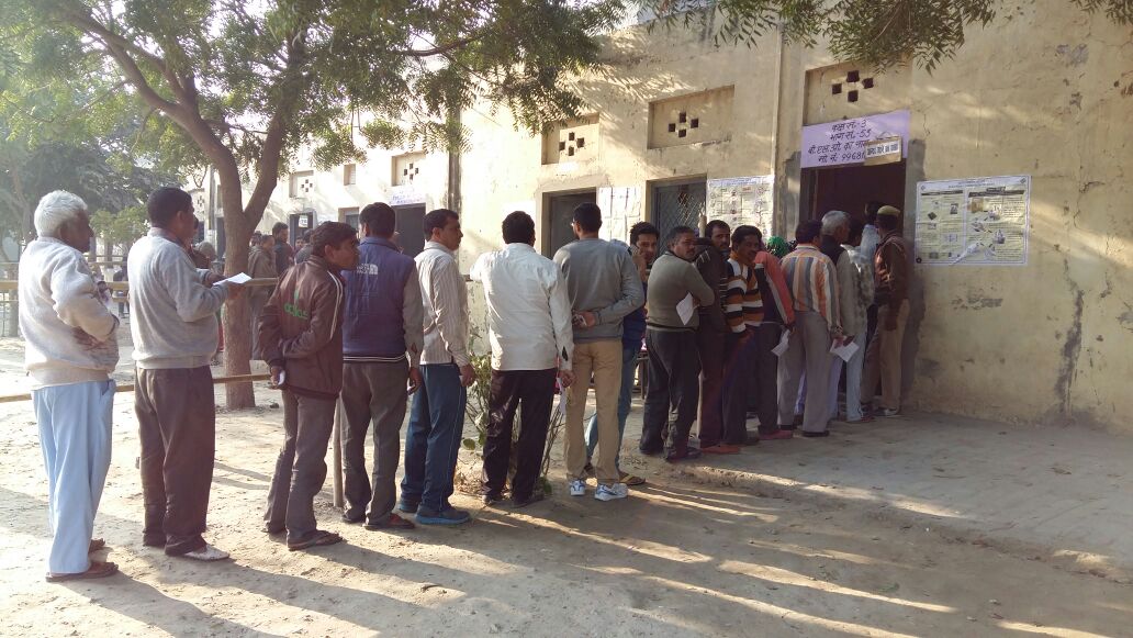 People queue up to cast their votes at the polling booth in Noida Sec-22