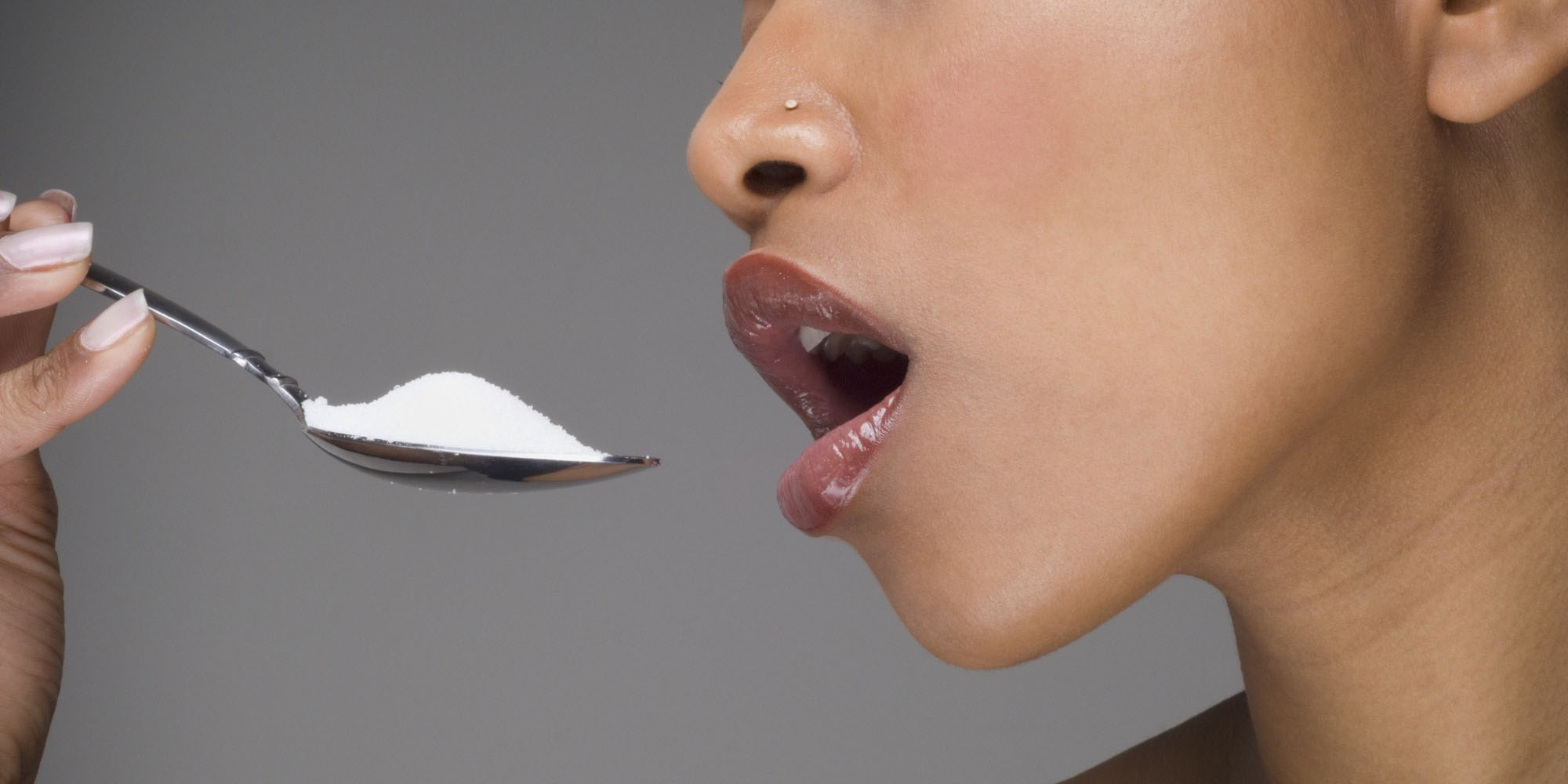 A woman having a spoon full of sugar 