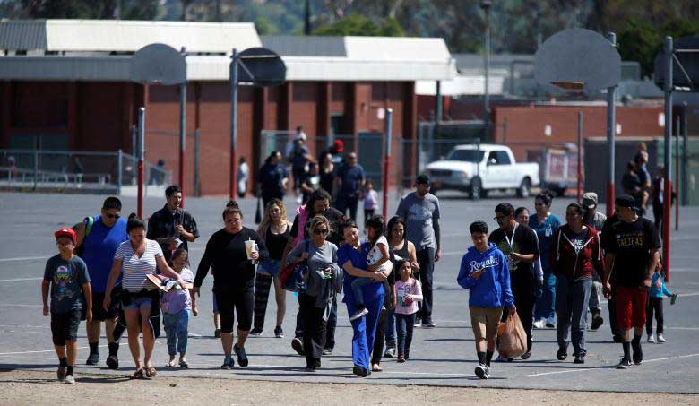 Students who were evacuated after a shooting at North Park Elementary School walk with their waiting parents at a high school in San Bernardino, California, US