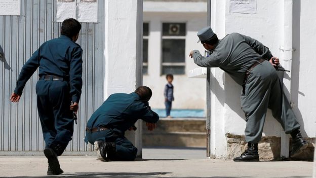 Afghan policemen try to rescue a child at the site of the attack