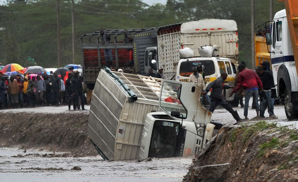 A man is assisted to climb off a truck that was washed off a road by flash floods at Isinya, southeast of Nairobi