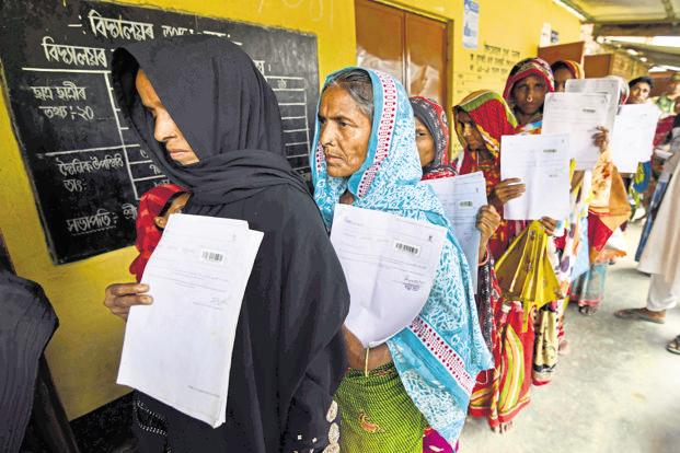 Residents hold their documents as they queue up to check their names on the final draft of NRC in Morigoan district of Assam