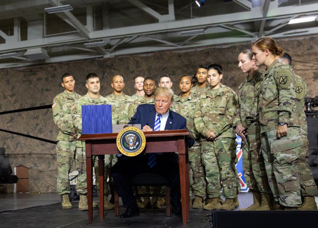 US President signing a US$716 billion defence policy bill