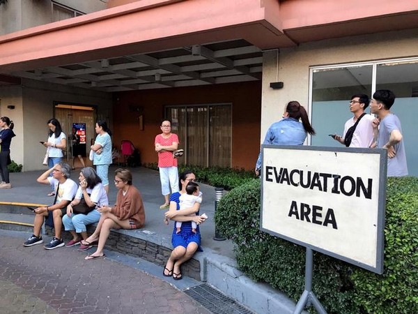 Residents sit outside after being evacuated from the condominium building after an earthquake in Makati City, Philippines