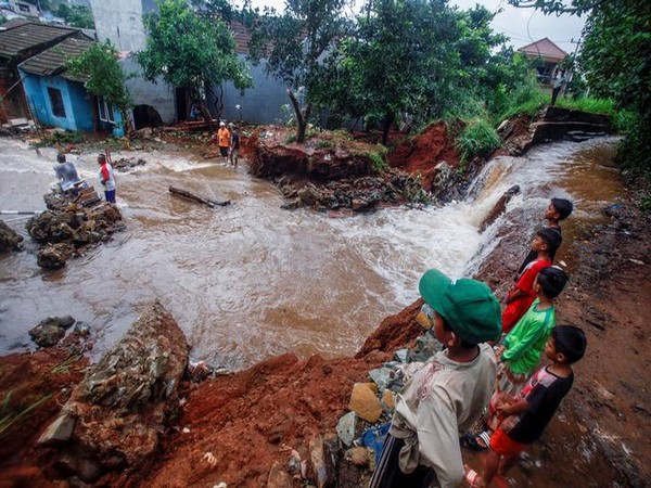 People look at a dam which collapsed after heavy rains in Bogor, West Java province, Indonesia
