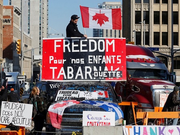 A person attaches a flag to a truck as truckers and their supporters continue to protest coronavirus disease (COVID-19) vaccine mandates, in Ottawa, Ontario.