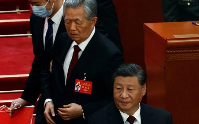 Former Chinese president Hu Jintao leaves his seat next to Chinese President Xi Jinping