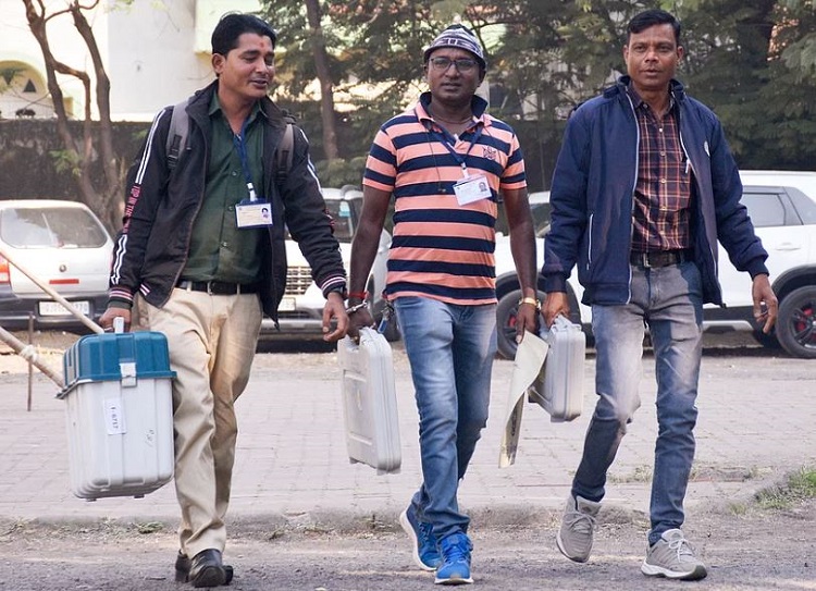 Polling officials carrying Electronic Voting Machines